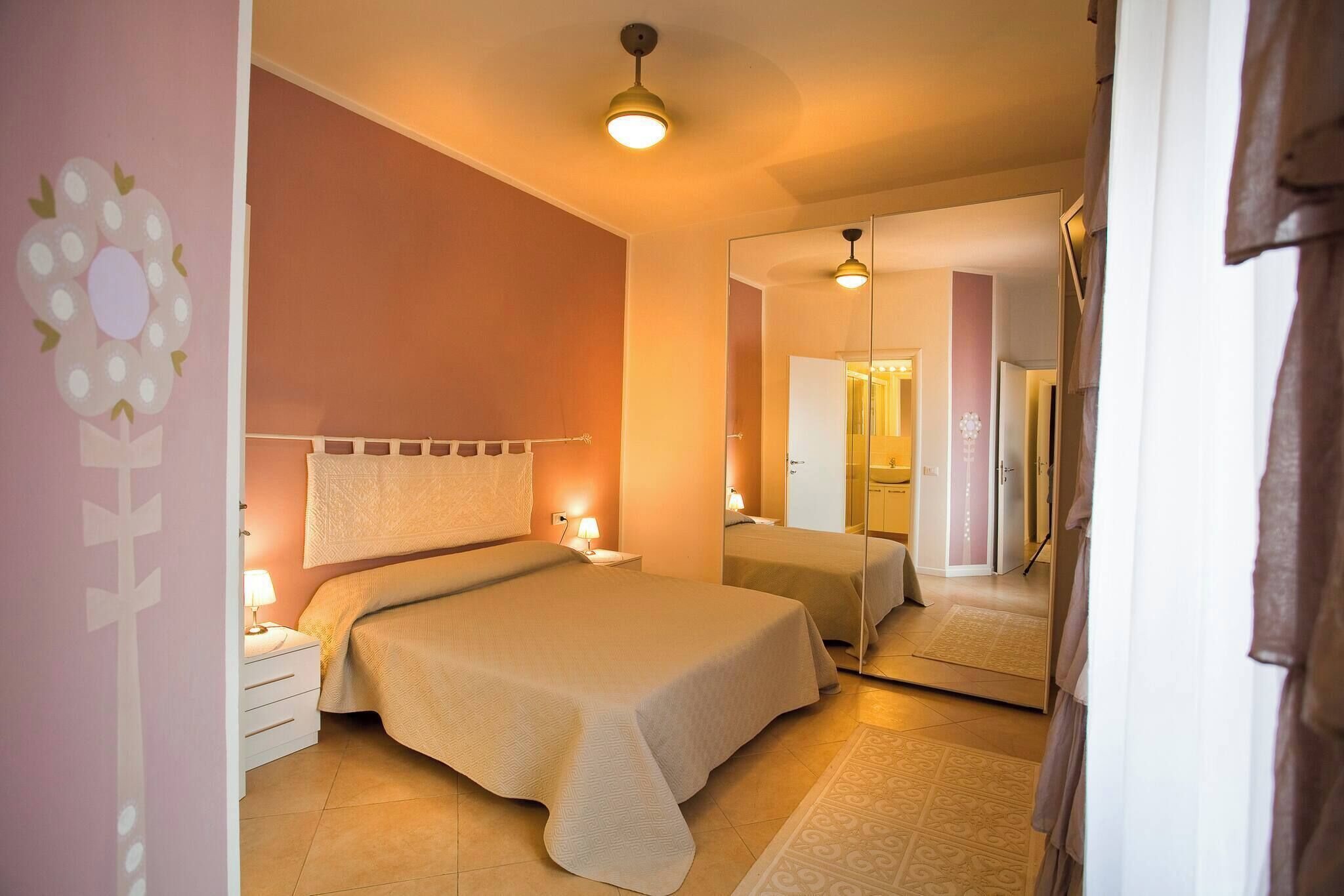 Une chambre à coucher avec un lit, des tables de chevet, un miroir et un luminaire au plafond.