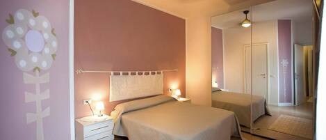 A bedroom with a bed, bedside tables, a mirror, and a wall decoration.