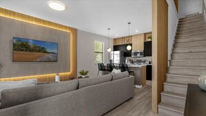 Una sala moderna con sofá, comedor, cocina y escalera.