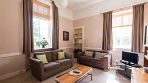 A living room with two sofas, a coffee table, a TV, and a bookshelf.