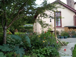 Une charmante maison avec un jardin à l’avant, une fenêtre bien visible et une clôture en bois.