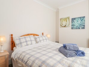A bedroom with a bed, a nightstand, a lamp, and two wall art pieces. - Southview Amble (Morpeth)