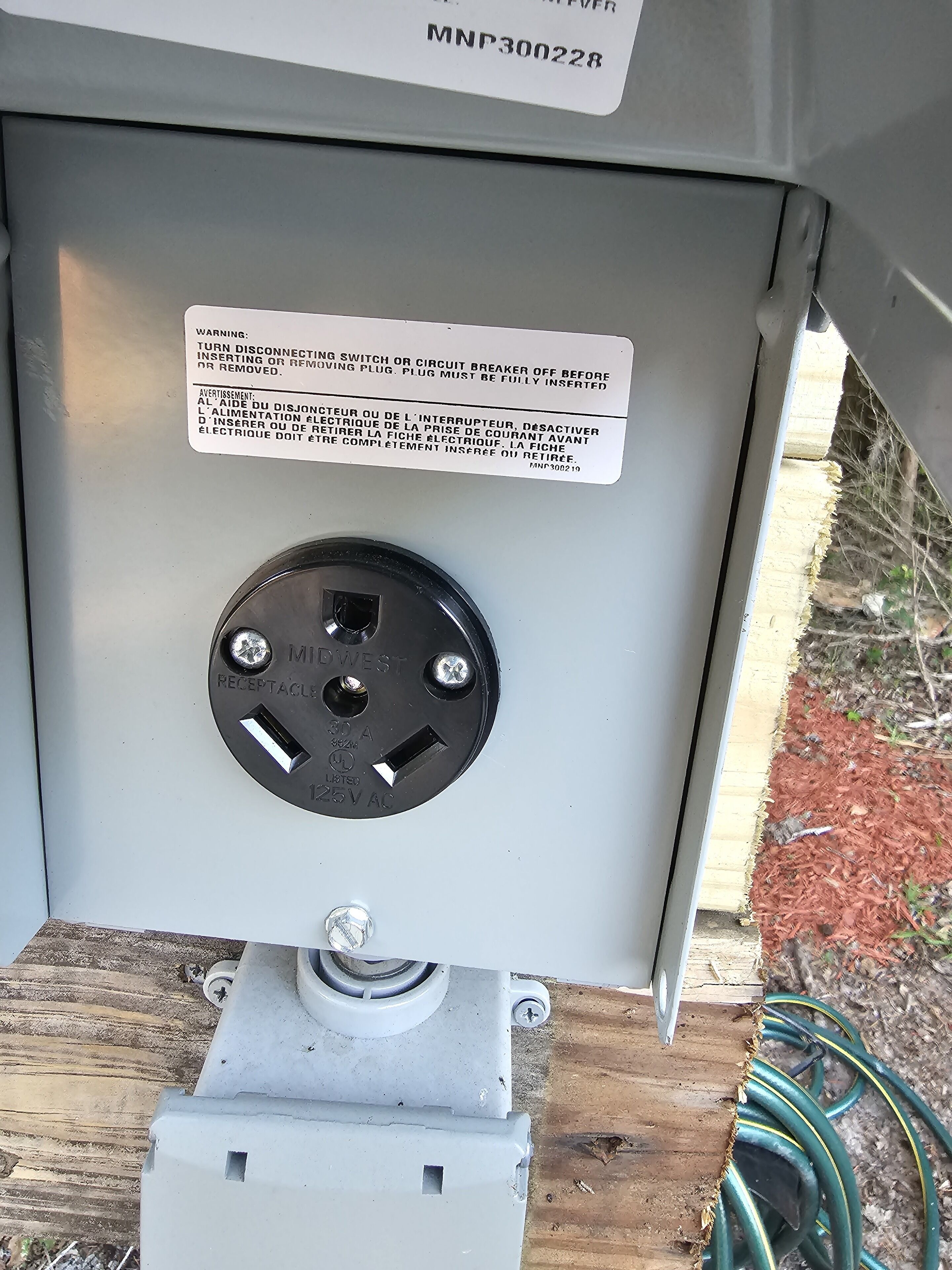 A utility box with a warning label and a circular electrical outlet.