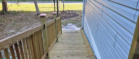 A wooden deck leading to a house with a blue siding exterior.