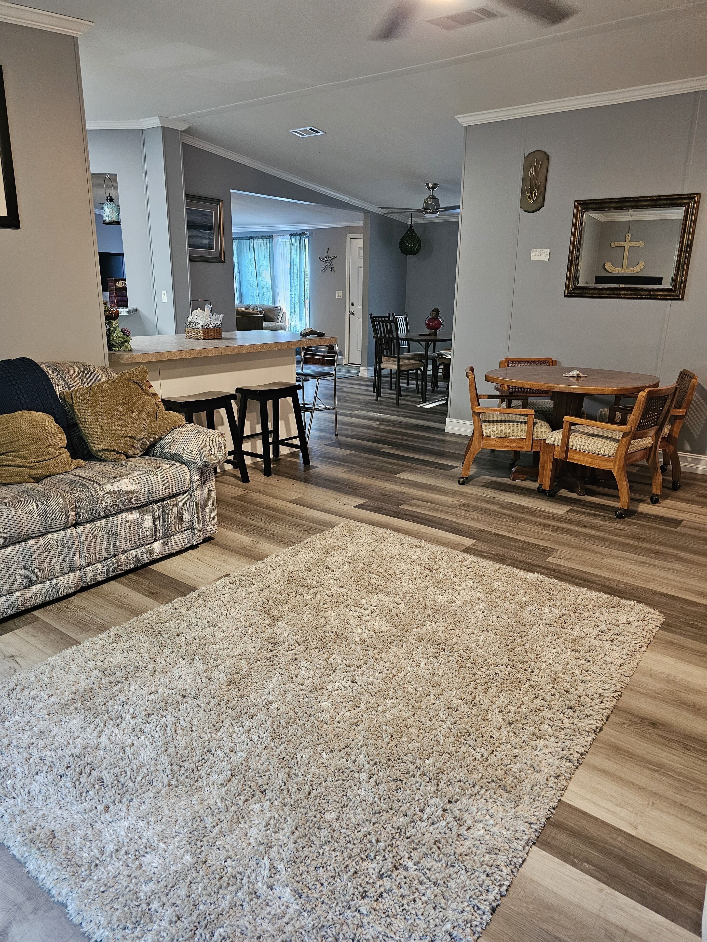 En stue med sofa, sofabord og spiseområde med bord og stole.