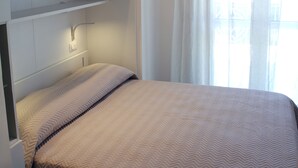 Un dormitorio con cama, armario empotrado y ventana con cortinas.