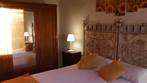 Un lit bien fait, avec deux oreillers, une lampe de chevet et un miroir au mur.