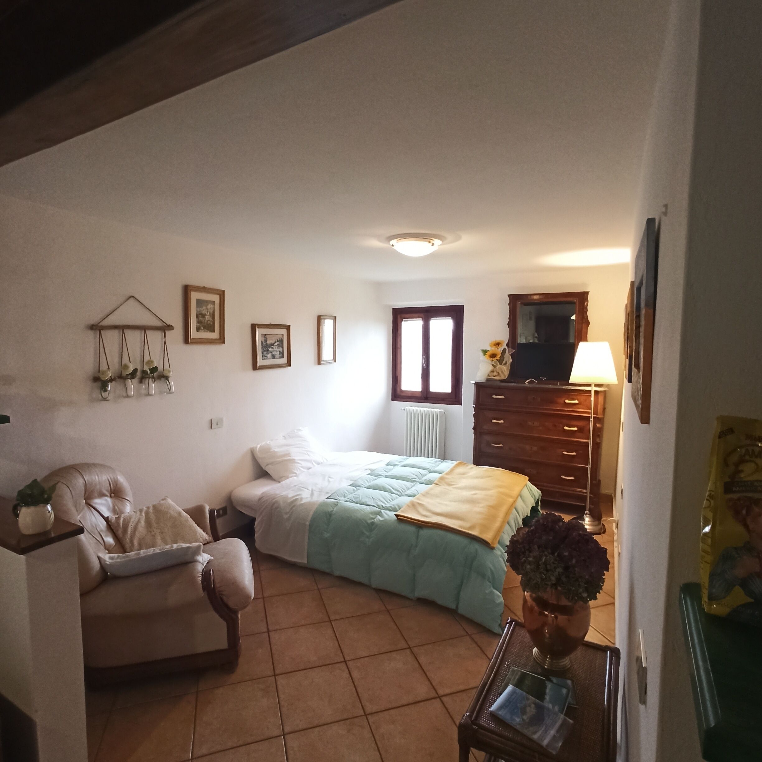 Une chambre à coucher avec un lit, une chaise, une commode et une petite table.
