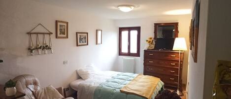 Une chambre à coucher avec un lit, une chaise, une commode et une petite table.