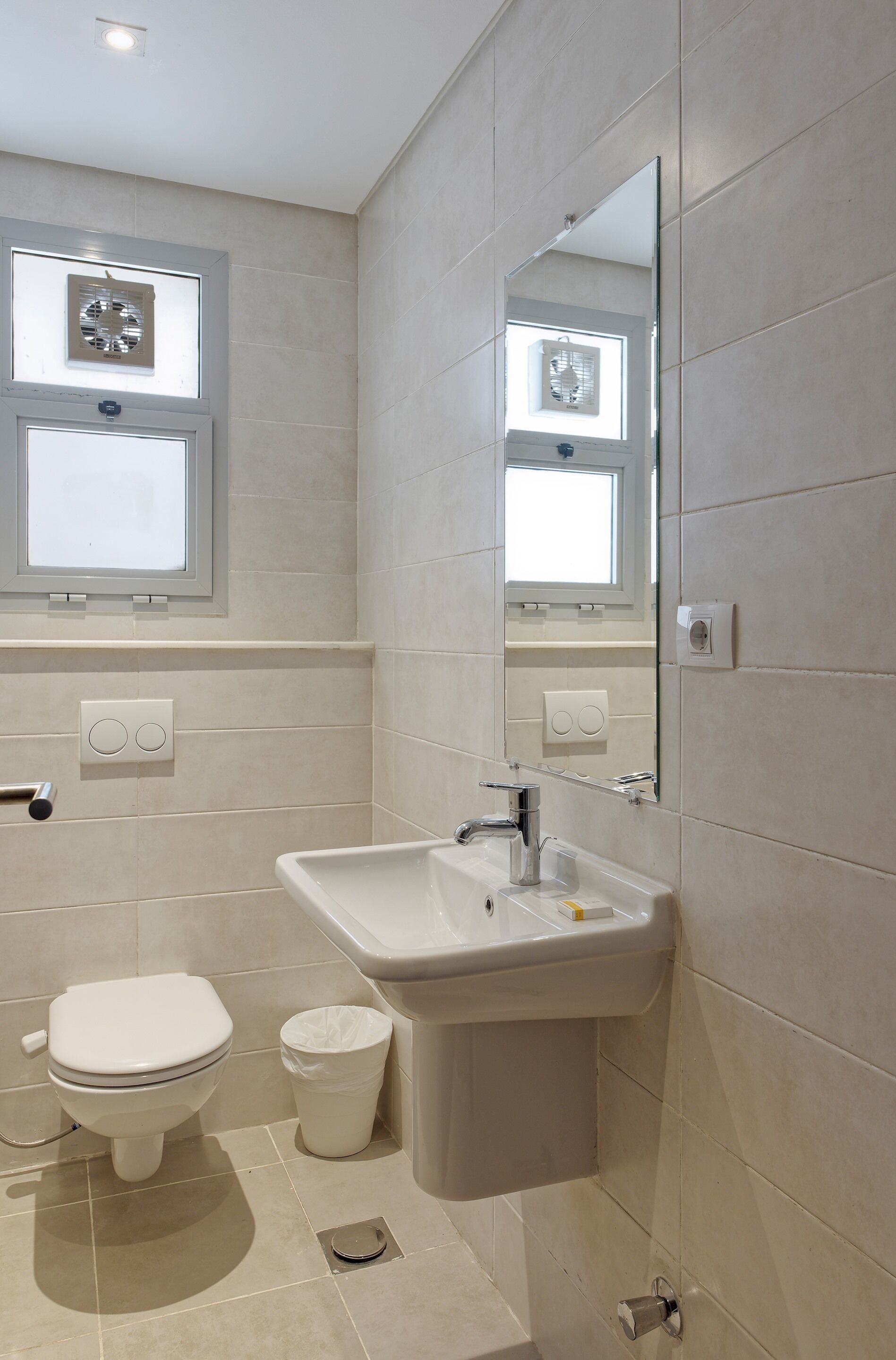 A modern bathroom with a toilet, sink, and mirror.
