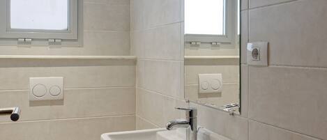 A modern bathroom with a toilet, sink, and mirror.