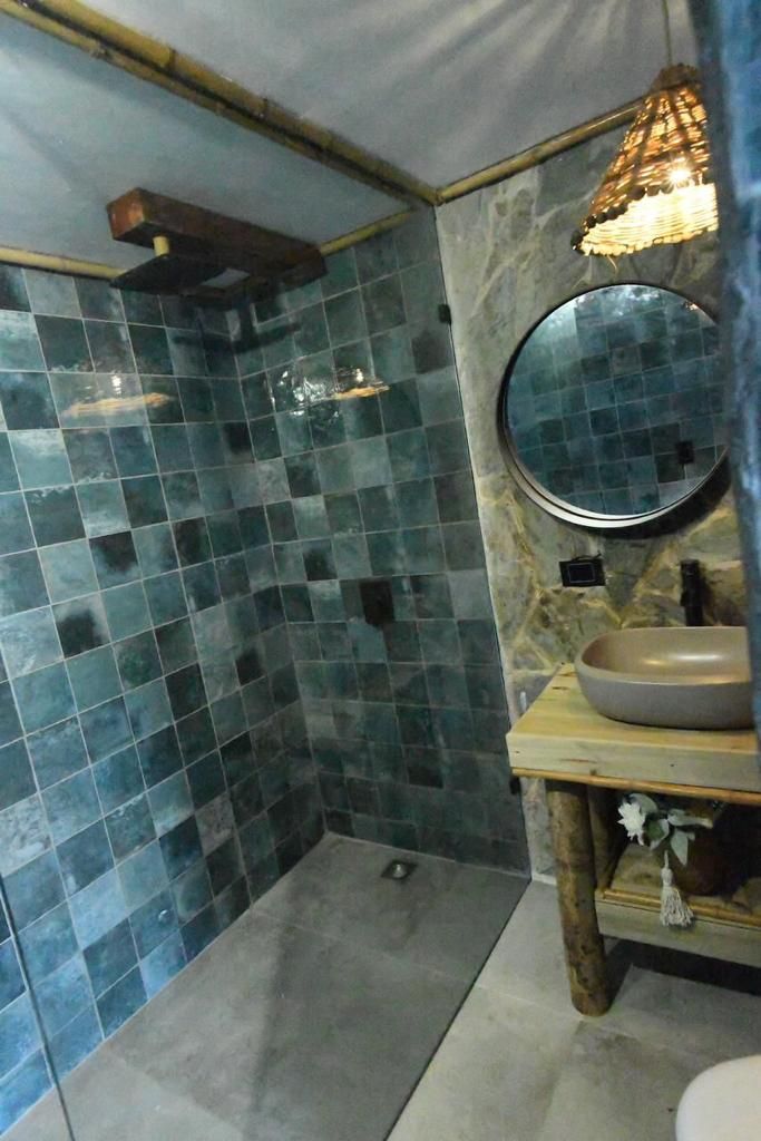 A bathroom with a shower area and a sink with a round mirror.