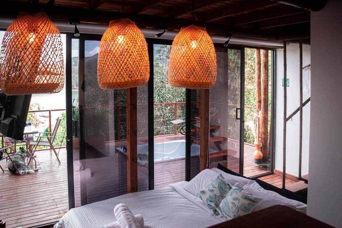 A bedroom with a bed, a glass door leading to an outdoor deck, and hanging lamps.