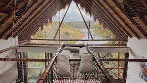 A high-roofed room with a view of a river and greenery. - Ibuku Hotel (El Peñol)