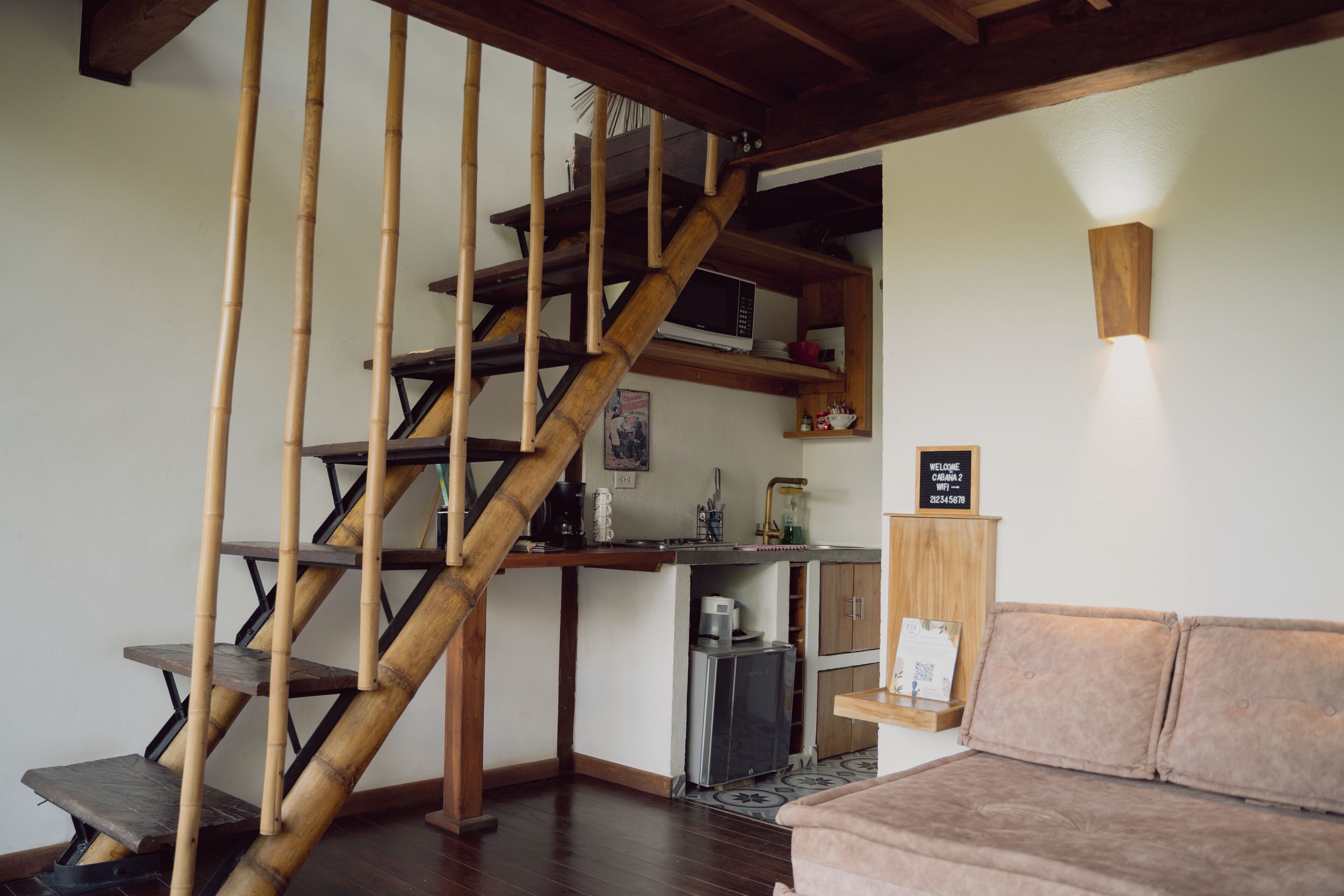 A staircase with a wooden finish, a kitchen area with a microwave, and a sofa in a living space.