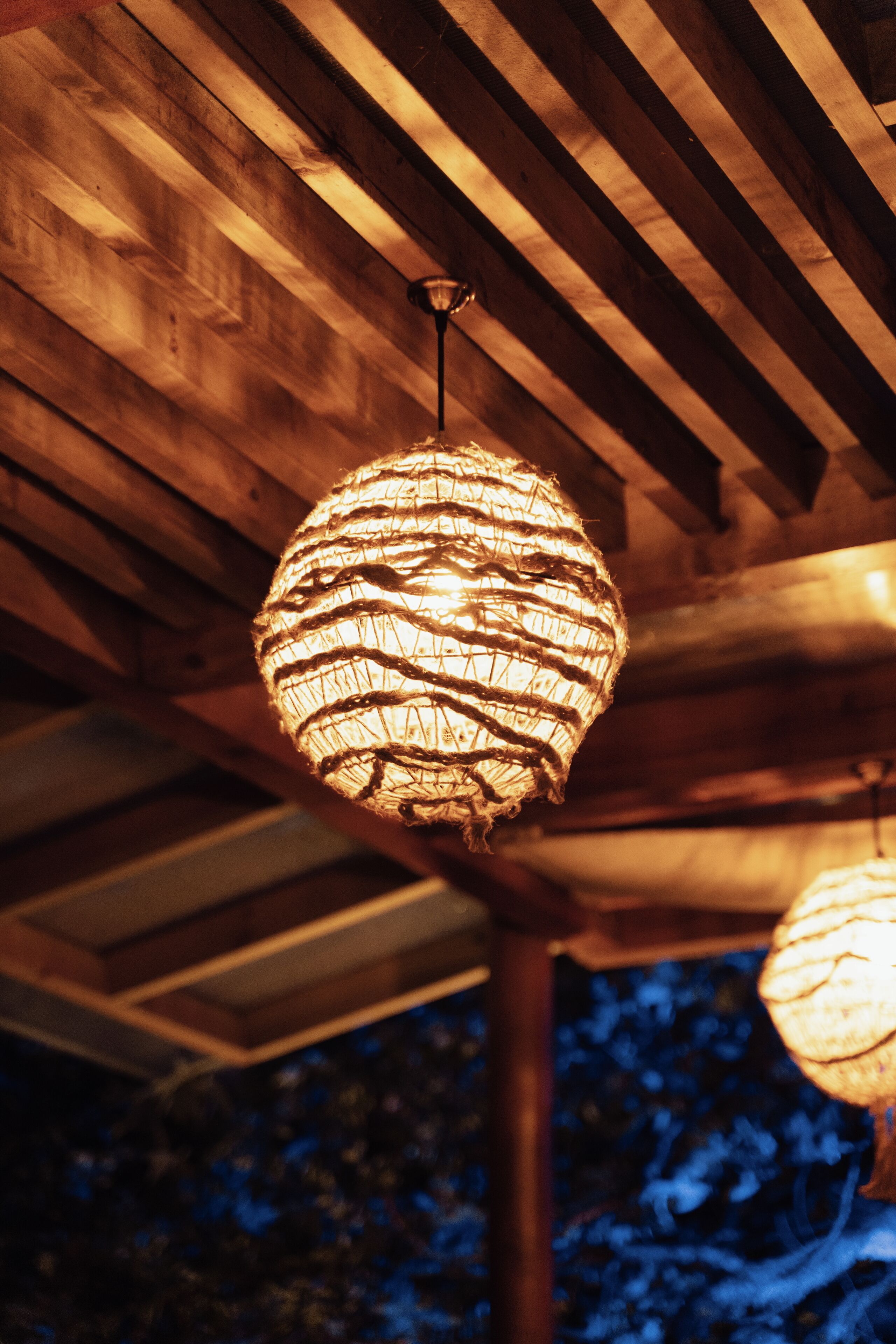 A wooden ceiling with a hanging spherical light fixture.