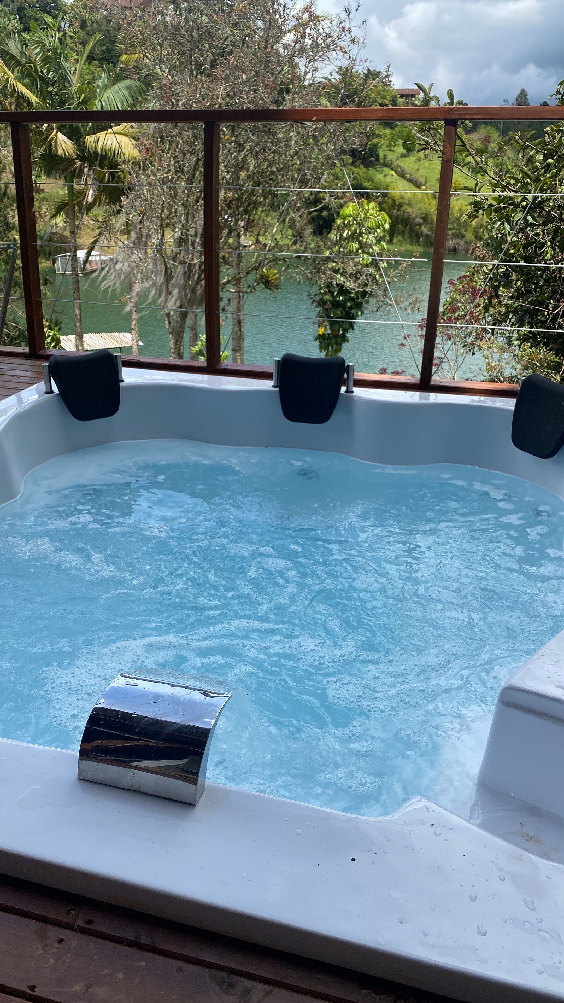 A hot tub with a view of a lake and surrounding greenery.