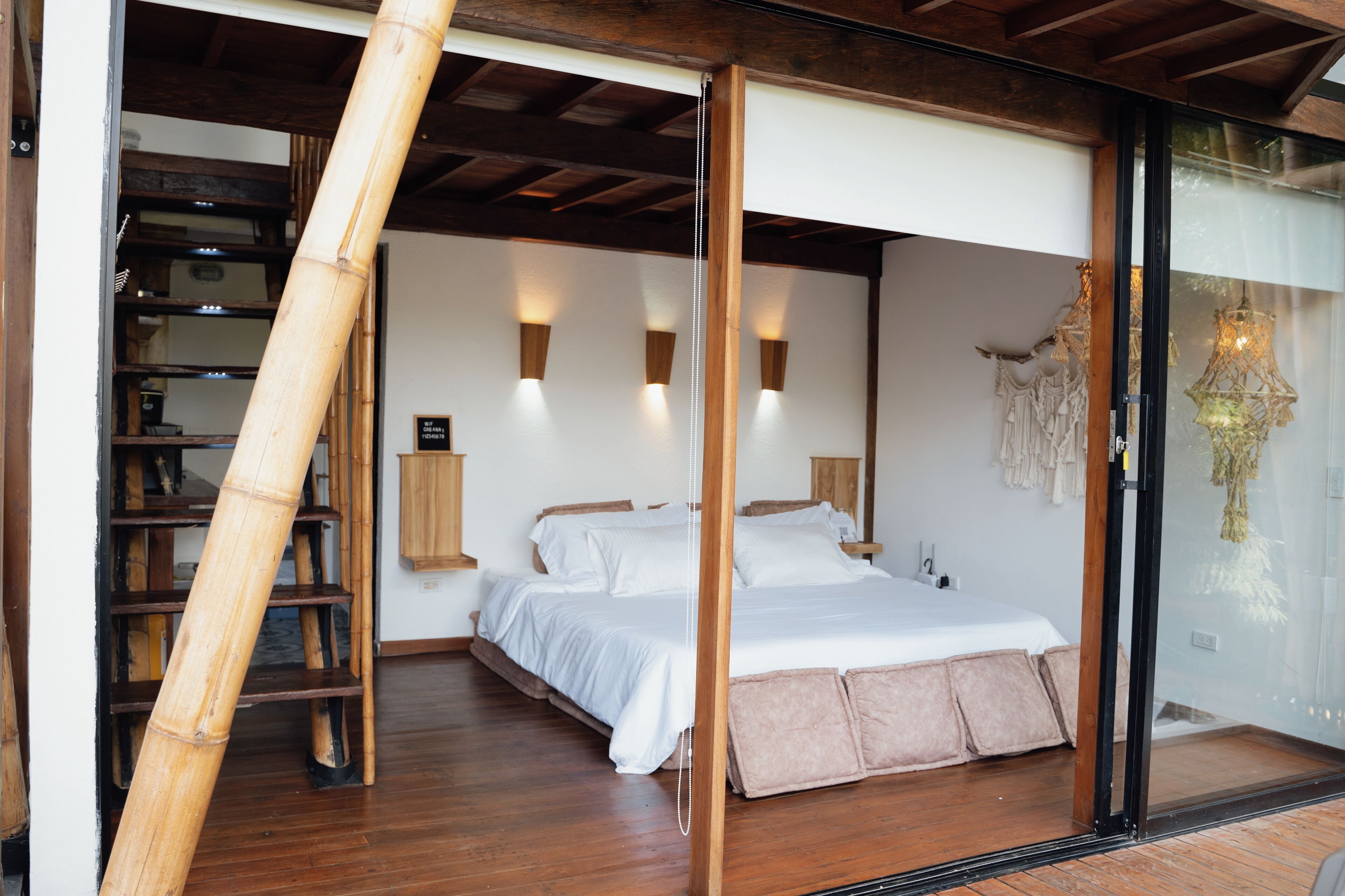 A bedroom with a bed, wooden floor, and a glass door leading to a balcony.