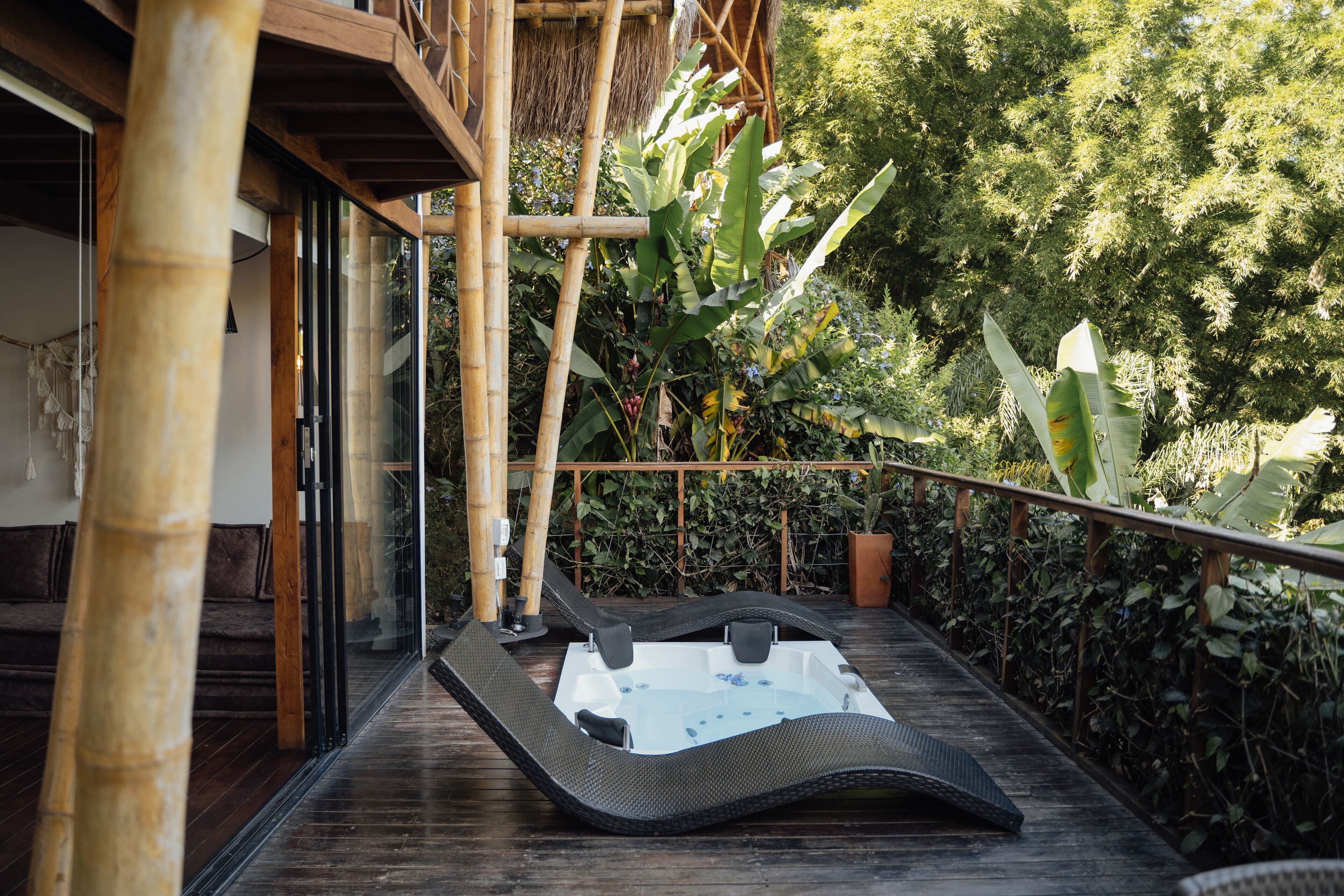 A hot tub on a wooden deck with bamboo structures and lush greenery in the background.