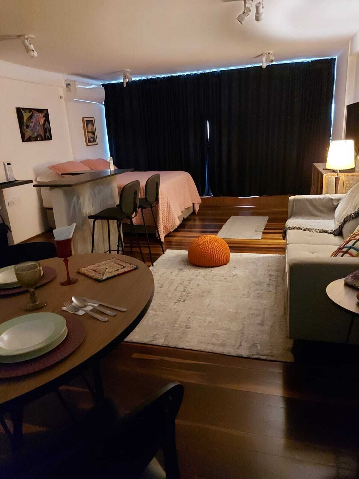 A compact living space with a kitchenette, a dining area, and a seating area with a sofa and ottoman.