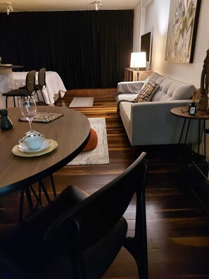 A cozy living room with a dining table, a sofa, and a coffee table.