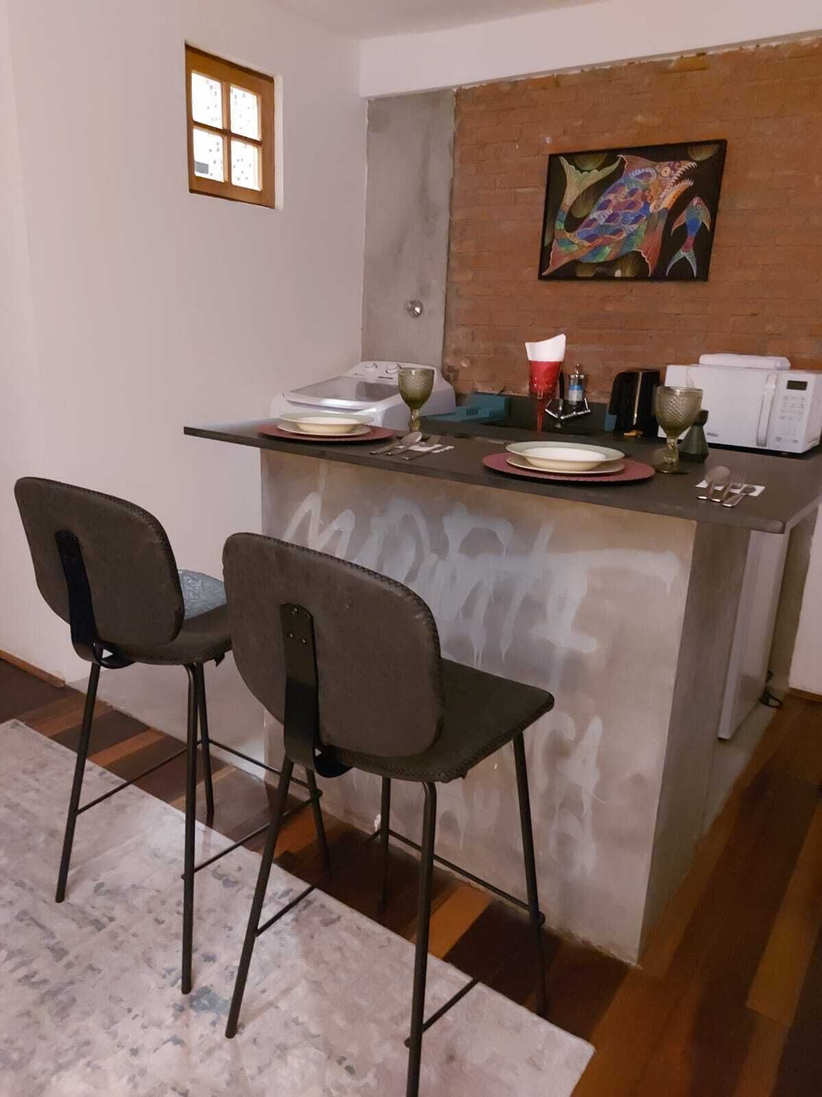Una pequeña cocina con comedor, que incluye un microondas, un lavamanos y un cuadro en la pared.