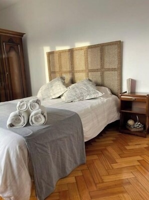 Cozy retreat with a large bed, wooden nightstand, and parquet floor.