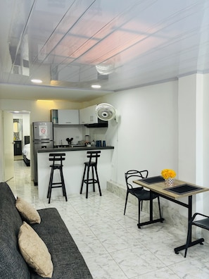 A modern kitchen with a central island, bar stools, a dining table with chairs, and a fan. - MAR DE INDIAS HOUSE (Cartagena)
