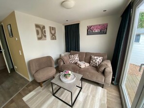 A living room with a sofa, armchair, coffee table, and artwork on the walls.