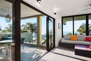 Un salon moderne doté d’une grande porte vitrée donnant sur un balcon, d’un canapé avec des coussins et d’une table basse.