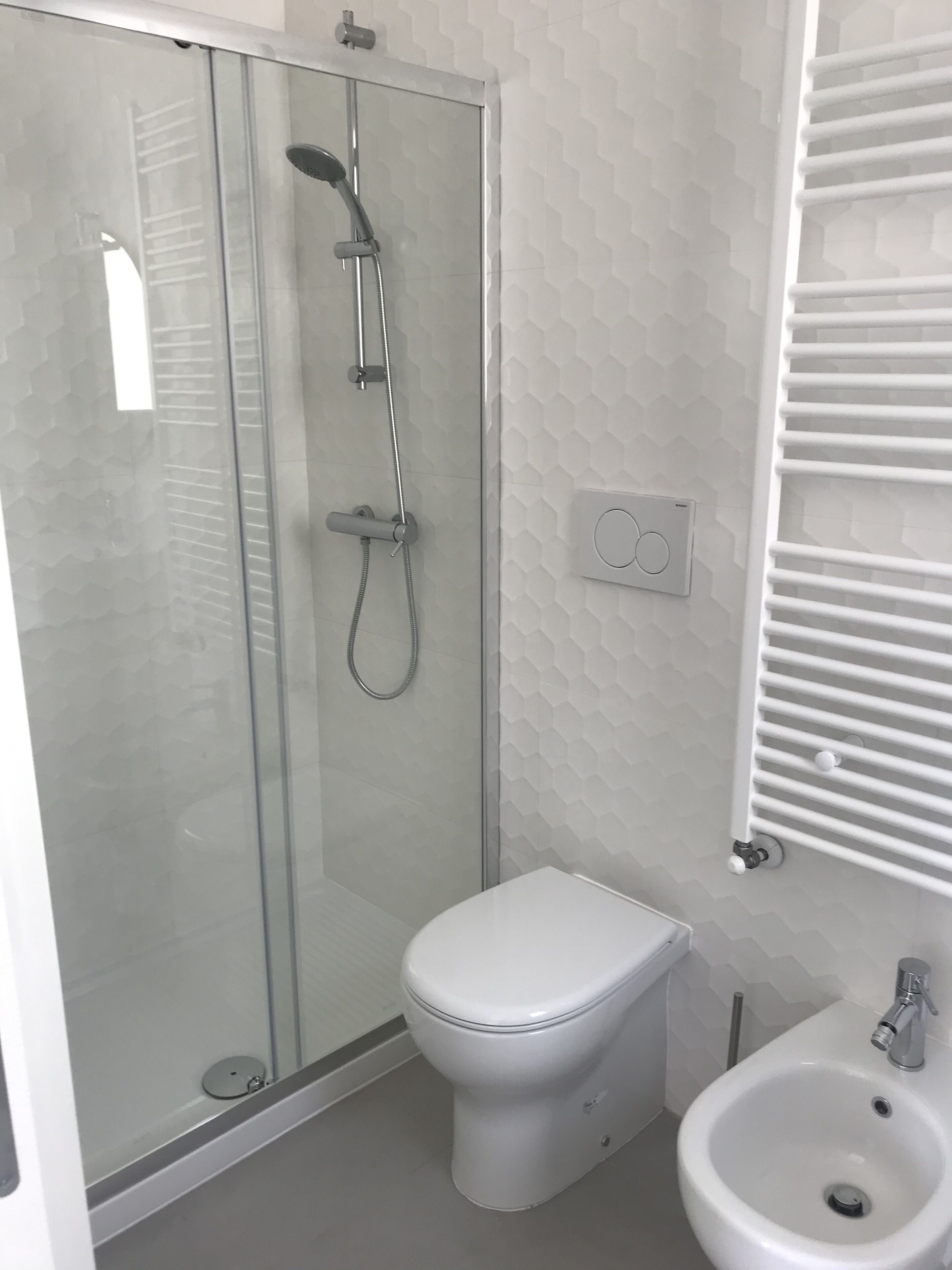 A modern bathroom with a glass-enclosed shower, a toilet, and a sink.