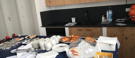 Una mesa con un bufé de desayuno, mostrando diferentes alimentos, platos y cubiertos.