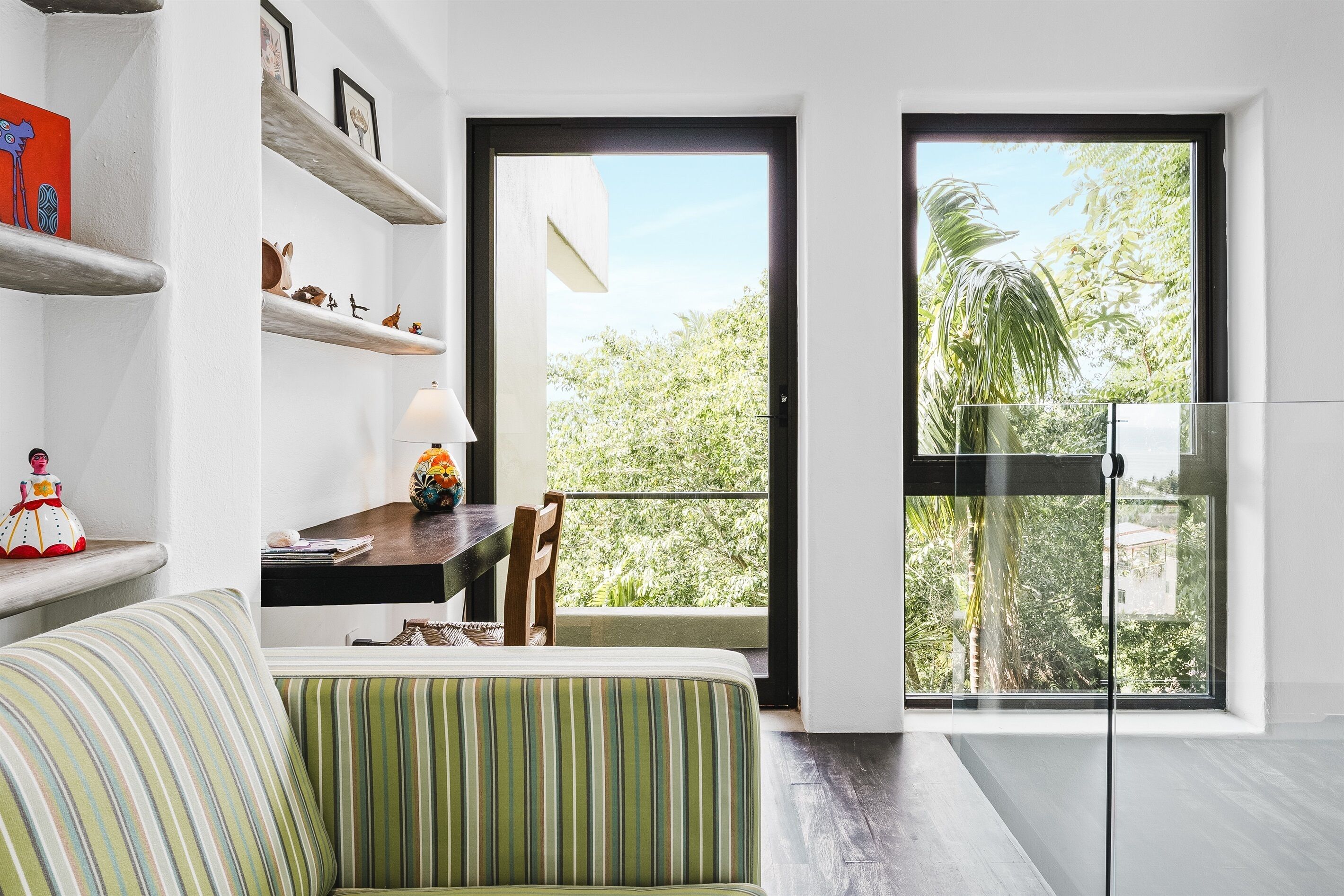 Un salon moderne avec un canapé, une table à manger et un balcon offrant une vue sur la verdure.