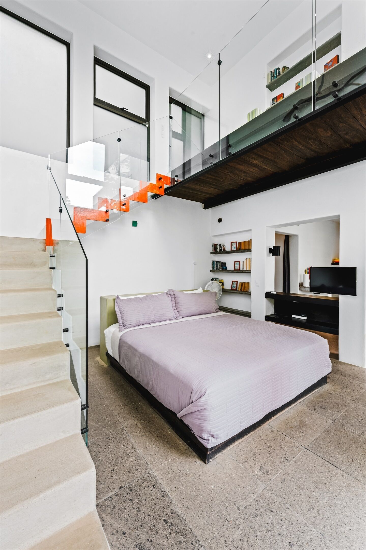 Camera da letto moderna con un letto grande, una scala e un televisore.