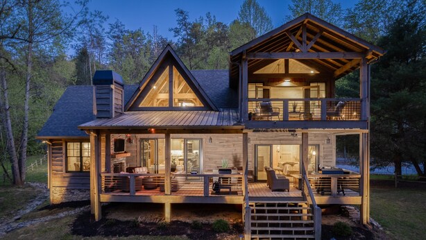 A two-story cabin with a deck, large windows, and a chimney.