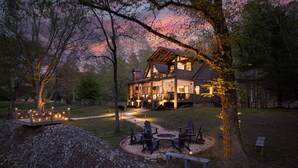 A rustic cabin with a deck, outdoor seating, and a fire pit.