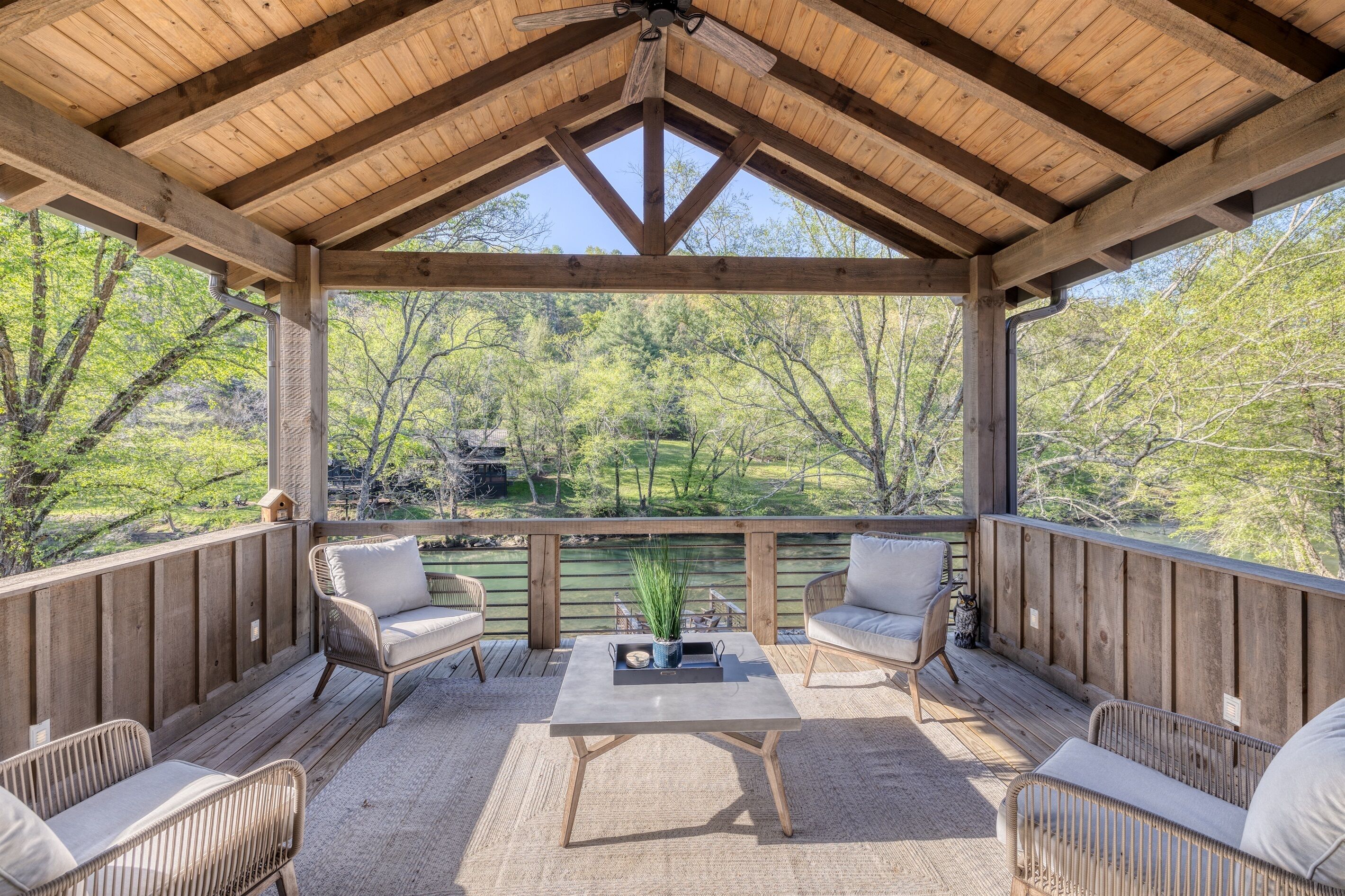 Un espace extérieur aménagé, abrité et doté de mobilier en osier et d’une table centrale, offrant une vue sur un paysage naturel.