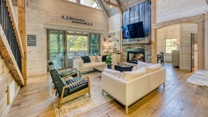 A spacious living area with a fireplace, wooden beams, and a large TV.