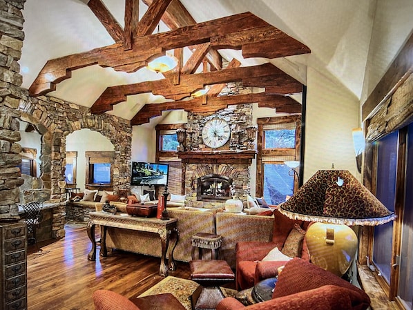 Cozy living room with a traditional stone fireplace, plush seating, and eclectic decor.