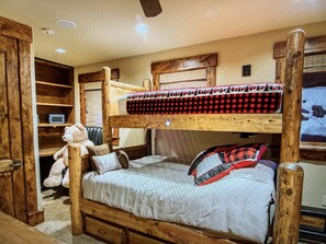 Cozy room with a bunk bed, wooden furniture, and a large teddy bear.