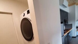 A laundry room with two washing machines and a kitchen area visible in the background. - Move-in ready lakeside retreat (Minerva)