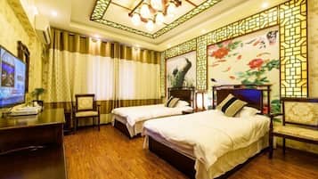 A hotel room with two beds, a desk with a television, and a decorative wall with a floral painting.