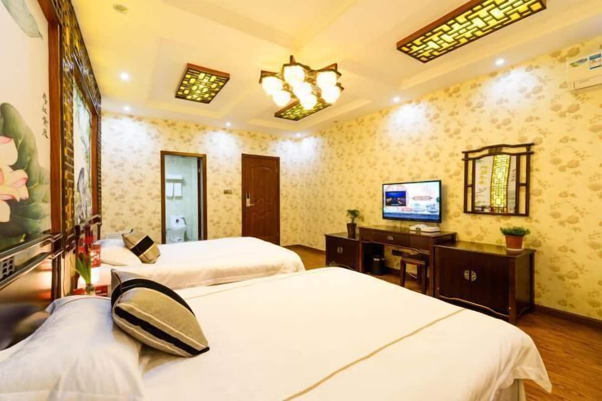 A hotel room with two beds, a TV, a desk, and a decorative ceiling light fixture.