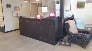 Zona de recepción con un mostrador de madera, un reloj y una silla con cojín.