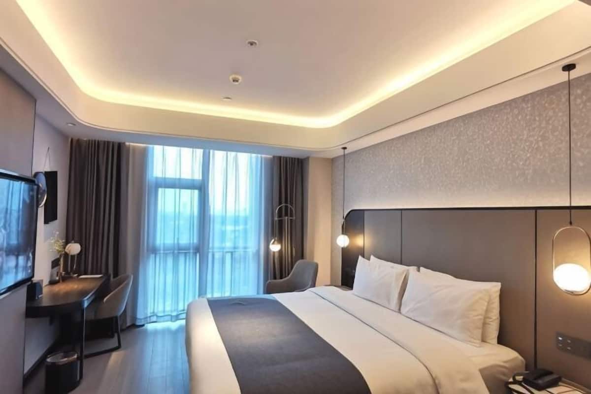 Una habitación de hotel moderna con una cama grande, un escritorio y un televisor.