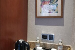 Ein Badezimmer mit Kaffeemaschine, Handseife und einem gerahmten abstrakten Gemälde an der Wand.
