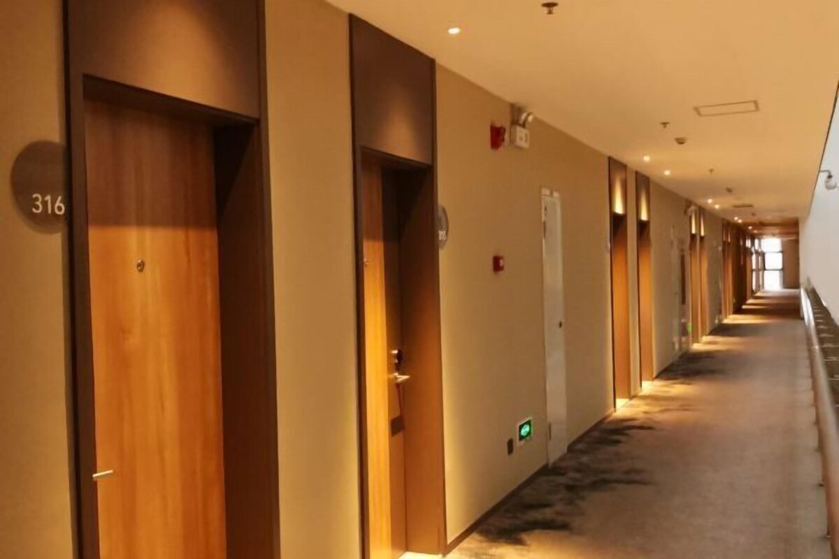 Ein Hotelgang mit Holztüren, darunter die Nummer 316, und einem Teppichboden.