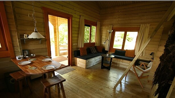 Un interno accogliente con un tavolo da pranzo in legno, una poltrona e un piccolo tavolino con una lampada.