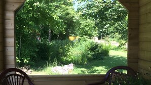 Un portico in legno con due sedie rivolte verso una vista su un giardino rigoglioso.