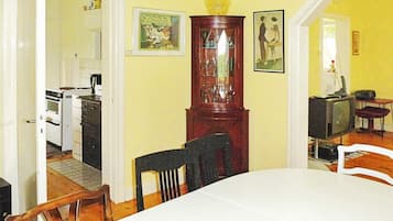 Un comedor con una mesa, sillas, un armario de madera y una cocina al fondo.